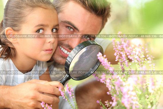 father and little daughter observing flowers with magnifying glass. Стоковое фото, агентство Ingram Publishing / Фотобанк Лори