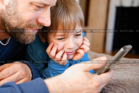 Father and son little boy laughing and using phone. They watching funny videos together, playing games on smartphone. Concept technology, smart phone addicted. Fun weekend activity. Modern fatherhood. Стоковое фото, фотограф Марина Демидюк / Фотобанк Лори