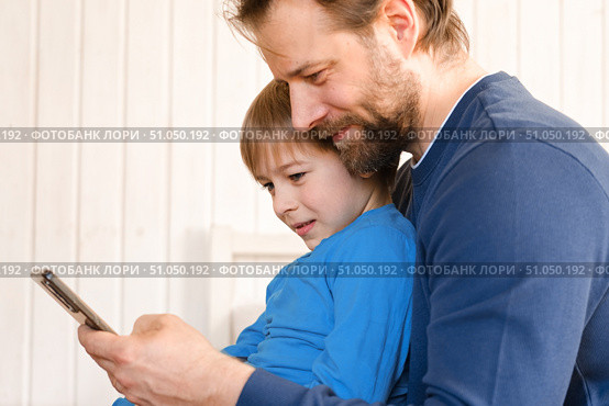 Father and son little boy laughing and using phone. They watching funny videos together, playing games on smartphone. Concept technology, smart phone addicted. Fun weekend activity. Modern fatherhood. Стоковое фото, фотограф Марина Демидюк / Фотобанк Лори