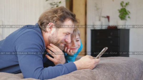 Father and son little boy laughing and using phone. They watching funny videos together, playing games on smartphone. Concept technology, smartphone addicted. Fun weekend activity. Modern fatherhood. Стоковое видео, видеограф Марина Демидюк / Фотобанк Лори