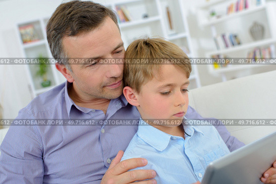 Father cuddling boy looking at computer. Стоковое фото, агентство Ingram Publishing / Фотобанк Лори
