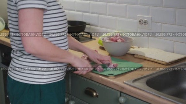 Female butcher cut raw meat with sharp knife at home kitchen. Woman cutting the chicken fillet in pieces for cooking. Preparing chopping food. Split poultry breast. Healthy lean meat, low cholesterol. Стоковое видео, видеограф Марина Демидюк / Фотобанк Лори