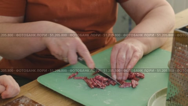 Female butcher cut raw meat with sharp knife at home kitchen. Woman cutting the chicken fillet in pieces for cooking. Preparing chopping food. Split poultry breast. Healthy lean meat, low cholesterol. Стоковое видео, видеограф Марина Демидюк / Фотобанк Лори