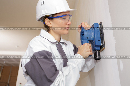 female construction worker smoothing wall surface. Стоковое фото, агентство Ingram Publishing / Фотобанк Лори