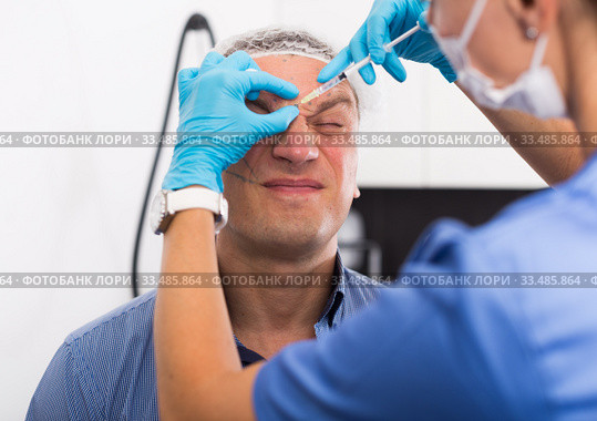 Female doctor is doing injection to patient in skin of face. Стоковое фото, фотограф Яков Филимонов / Фотобанк Лори