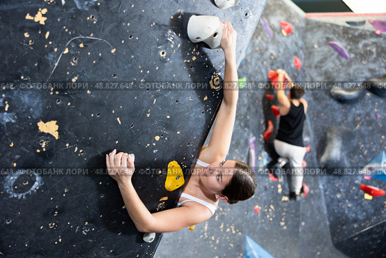 Female fitness climber training at bouldering gym. Young woman rise up on artificial climbing wall. Стоковое фото, фотограф Яков Филимонов / Фотобанк Лори