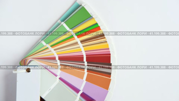 Female Hand opening Color guide close up. Assortment of Colour samples for design. Colors palette fan on white concrete wall background. Graphic designer chooses colors. Coloured swatches catalogue 4K. Стоковое видео, видеограф Марина Демидюк / Фотобанк Лори