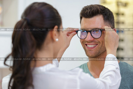 female optician fitting male clients eyeglasses. Стоковое фото, агентство Ingram Publishing / Фотобанк Лори
