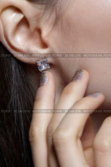 Female posing with hand near face. In the ear is an earring with a white crystal stone. Стоковое фото, фотограф Сергей Пристяжнюк (Serg Zastavkin) / Фотобанк Лори