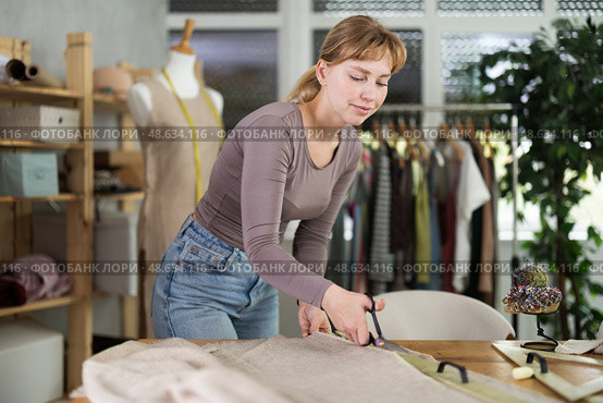 Female seamstress cutting fabric with scissors on worktable. Стоковое фото, фотограф Яков Филимонов / Фотобанк Лори
