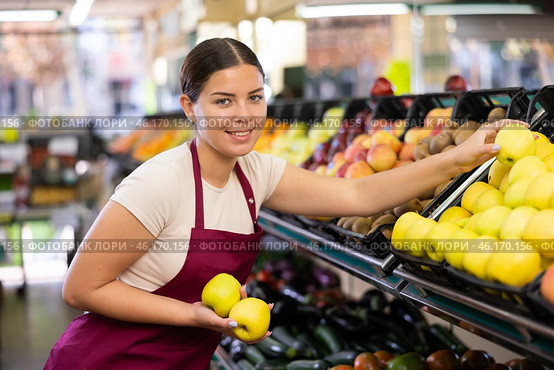 Female seller in apron chooses juicy apple. Стоковое фото, фотограф Яков Филимонов / Фотобанк Лори