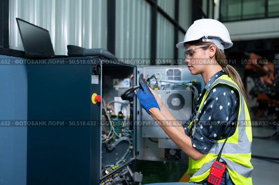 Female Technician Inspecting and repairing robotics arm in robots hangar and test the operation of the machine after being used for a while, as well as updating the software and calibration. Стоковое фото, агентство Ingram Publishing / Фотобанк Лори
