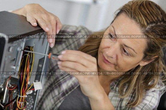 female  unscrewing a back of a laptop. Стоковое фото, агентство Ingram Publishing / Фотобанк Лори