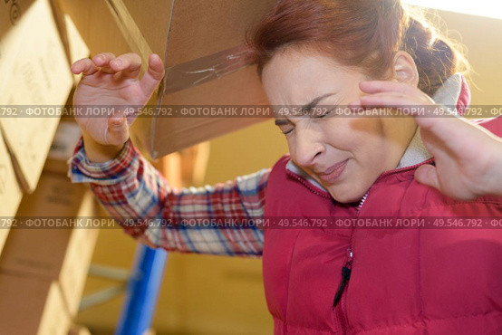 female worker hitting her head by accident into shelf. Стоковое фото, агентство Ingram Publishing / Фотобанк Лори