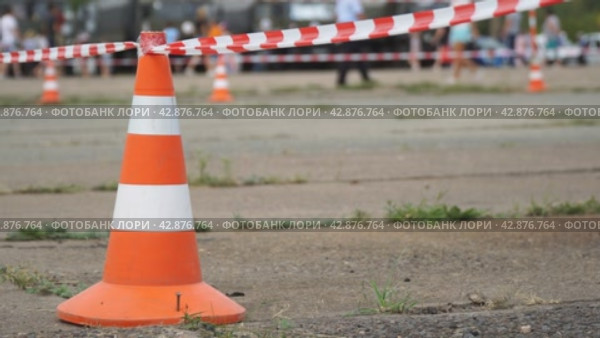 Fencing tape and road cone on the background of passing people. Selective focus. Стоковое видео, видеограф Александр Прошкин / Фотобанк Лори