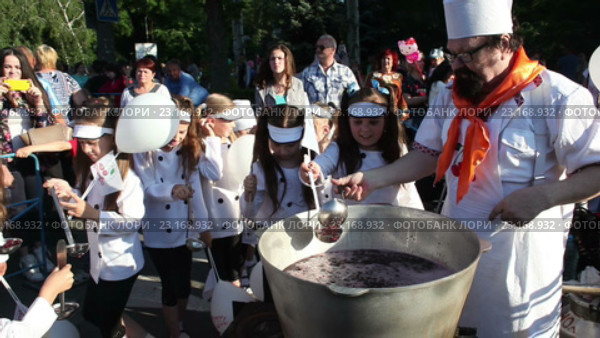 Фестиваль «Вишня 2016». Мелитополь. Украина. Шеф-повар мужчина раздаёт детям вишнёвое варенье из большого котла. 10 июня 2016 года. Редакционное видео, видеограф Сергей Мнацаканов / Фотобанк Лори