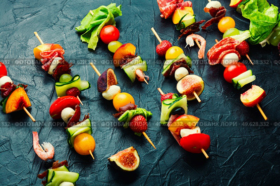 Festive snack of shrimps, jamon, fruits and vegetables on wooden skewers.. Wooden skewers with shrimps, meat and fruits. Стоковое фото, агентство Ingram Publishing / Фотобанк Лори