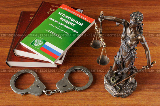 Фигурка Фемиды, наручники и Уголовный кодекс на деревянном столе. Стоковое фото, фотограф Денис Ларкин / Фотобанк Лори