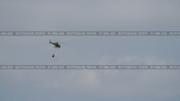 Firefighting helicopter flying with bambi bucket. Стоковое видео, видеограф Данил Руденко / Фотобанк Лори