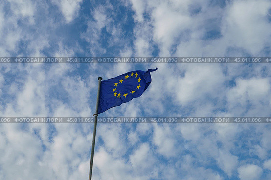 Flag of Europe (blue background and twelve five -pointed yellow stars). Flags blowing on the wind in a sunny summer day. Flags against blue sky background. (2019 год). Стоковое фото, фотограф YuryKara / Фотобанк Лори
