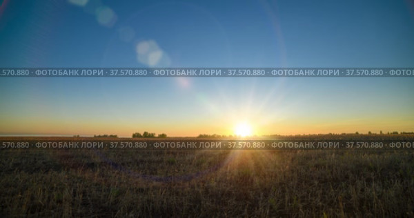 Flat hill meadow timelapse at the summer sunset time. Wild nature and rural grass field. Sun rays and green trees. Motorised dolly slider and panorama. Стоковое видео, видеограф Александр Маркин / Фотобанк Лори