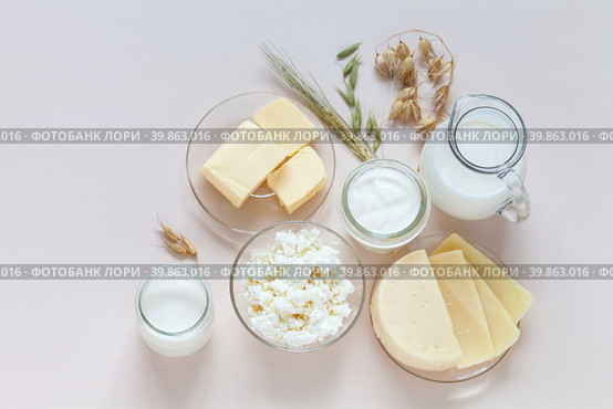 Flat lay of fresh dairy products - milk, cottage cheese, yogurt, sour cream, butter and oat ears on light background. Organic farm natural healthy food. Place for text. Tip view, closeup, copy space, mock up. Стоковое фото, фотограф Виктория Катьянова / Фотобанк Лори