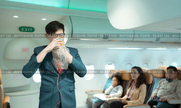 Flight attendants show how to use safety devices and recommend emergency exits. Стоковое фото, агентство Ingram Publishing / Фотобанк Лори