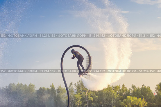 Flyboarding activity in a scenic outdoor location during sunset with a flyboard athlete soaring above the water. Acrobatics on a flyboard, somersaults and splashes. Стоковое фото, фотограф Владимир Разгуляев / Фотобанк Лори