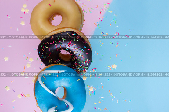 flying doughnuts on blue. flying doughnuts border - mix of multicolored sweet donuts with sprinkles on blue and pink background. Стоковое фото, агентство Ingram Publishing / Фотобанк Лори