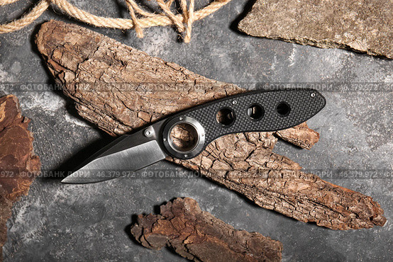 Folding pocket knife with rubberized handle and tree barks on textured background. Стоковое фото, фотограф Pixel_shot / Фотобанк Лори