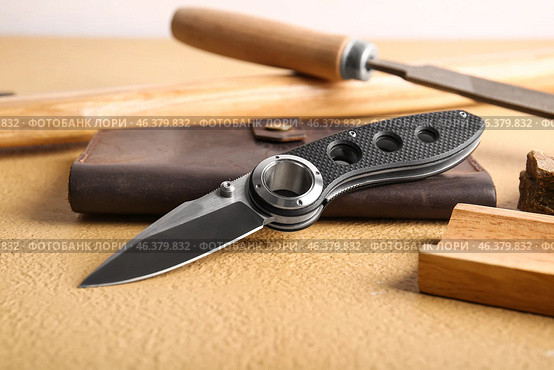 Folding pocket knife with rubberized handle on table. Стоковое фото, фотограф Pixel_shot / Фотобанк Лори