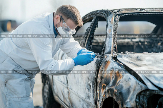 Forensic scientist examining burned car for evidence after fire incident. Стоковое AI-изображение, AI-художник Юрий Поздников / Фотобанк Лори