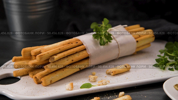 Fresh baked homemade grissini bread sticks in white ceramic tray with olive oil and basil herbs over kitchen counter top. Стоковое фото, агентство Ingram Publishing / Фотобанк Лори