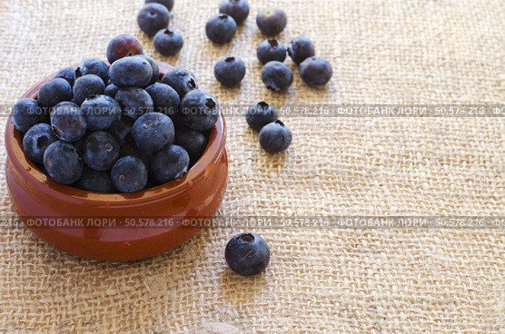 Fresh blueberries in clay bowl on sacking  background witj copyspace. Стоковое фото, агентство Ingram Publishing / Фотобанк Лори