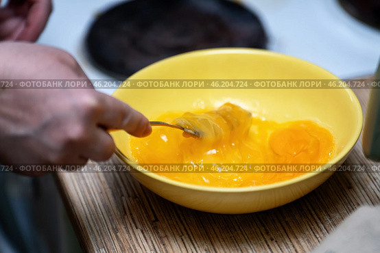 Fresh chicken eggs being whisked with a fork in a vibrant yellow ceramic plate, perfect for preparing a delicious omelette. Стоковое фото, фотограф Татьяна Степанищева / Фотобанк Лори