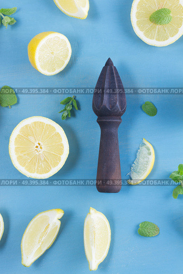 Fresh lemon citrus fruits slices with mint leaves and citrus reamer on blue bakground. Fresh lemon fruits. Стоковое фото, агентство Ingram Publishing / Фотобанк Лори