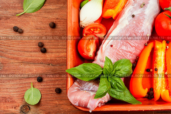 Fresh roasting meat in a baking dish with peppers, tomatoes and spices. Copy space.. Raw fresh meat fillet on wooden background. Стоковое фото, агентство Ingram Publishing / Фотобанк Лори