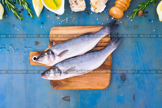 fresh sea fish preparation - top view of two raw seabass fish on cutting board. fresh sea fish preparation. Стоковое фото, агентство Ingram Publishing / Фотобанк Лори