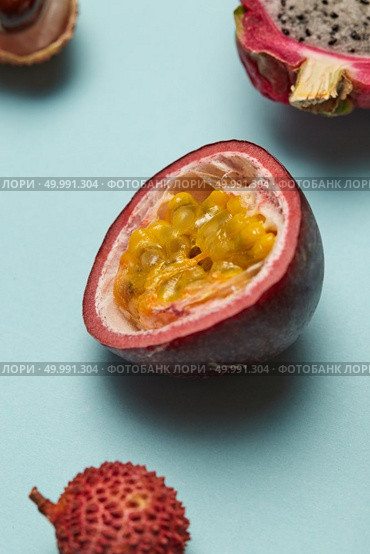 Fresh tropical half of passion fruit with delicious pulp and with lychee and dragon fruit on a blue background. Half of passion fruit with litchi and dragon fruit on a blue background. Стоковое фото, агентство Ingram Publishing / Фотобанк Лори