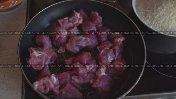 Fried meat in frying pan with rice bowl for homemade pilaf cooking. Стоковое видео, видеограф Андрей Знаменский / Фотобанк Лори