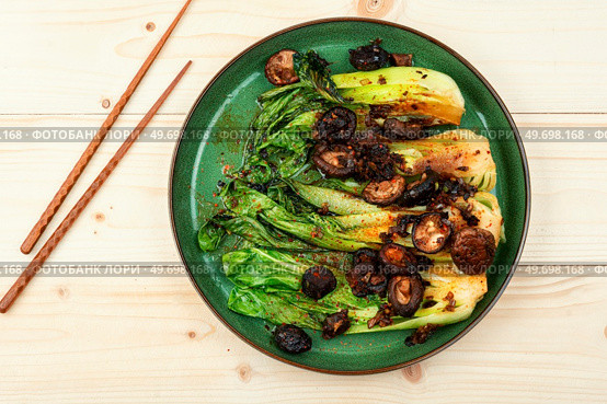 Fried Pak Choi with shitake mushrooms and chopstick on wooden table. Fried Chinese cabbage pak choi. Стоковое фото, агентство Ingram Publishing / Фотобанк Лори