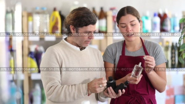 friendly female sales assistant presenting different fragrances, helping customer choose perfect scent. Стоковое видео, видеограф Яков Филимонов / Фотобанк Лори