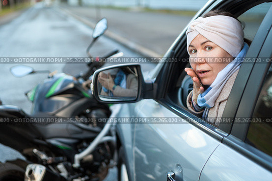 Frightened lady driver sitting inside car after road accident with motorcycle. Стоковое фото, фотограф Кекяляйнен Андрей / Фотобанк Лори