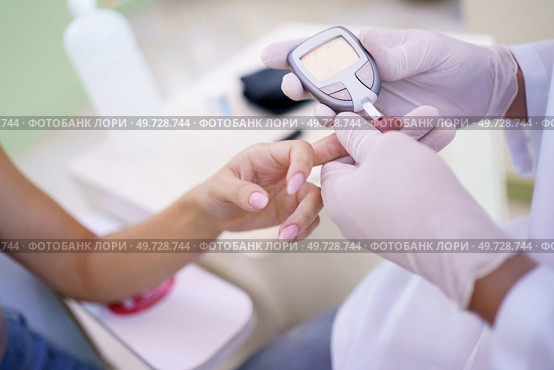 From above of crop anonymous hands of doctor in gloves checking blood sugar level of patient with glucometer in clinic. Doctor checking blood sugar level of patient in hospital. Стоковое фото, агентство Ingram Publishing / Фотобанк Лори