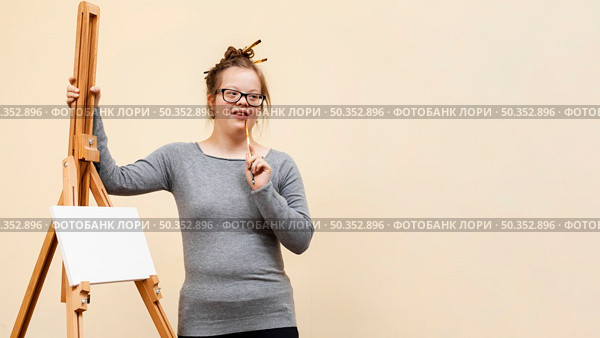 front view girl down syndrome posing easel. Стоковое фото, агентство Ingram Publishing / Фотобанк Лори