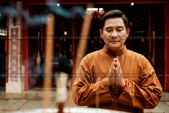 front view man praying temple with incense. Стоковое фото, агентство Ingram Publishing / Фотобанк Лори
