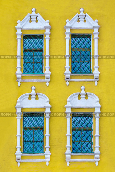 Front view on a facade of ancient yellow building with four windows with carved white stone platbands  as texture (vertical orientation) (2018 год). Стоковое фото, фотограф Михаил Строгалев / Фотобанк Лори
