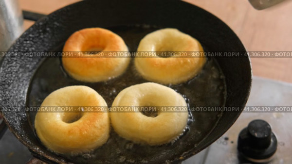 Frying process homemade and delicious donuts on fresh oil in a pan. Blue sugar topping on donuts in a home candy workshop. Pastry, sweet. Making dessert being deep fried. Preparation of donuts. Стоковое видео, видеограф Марина Демидюк / Фотобанк Лори