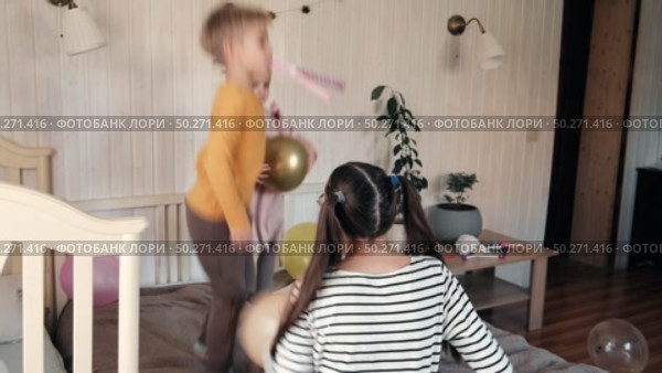 Fun Kids Celebration with Colorful Balloons, Party Horn Blowers and Festive Hats. Joyful Siblings Children Playful Little Girls and a Boy Dancing, Jumping, Playing among Golden Decorations. Party Time. Стоковое видео, видеограф Марина Демидюк / Фотобанк Лори