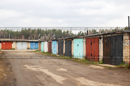 Garages lined up next to a dirt road under cloudy sky. Стоковое фото, фотограф Аксенова Вера / Фотобанк Лори